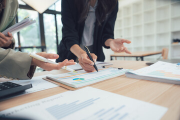 Focused Insights: Professionals gather, heads bowed, over reports, exchanging ideas. Their faces etched with concentration, the room hums with strategic energy. © Nittaya