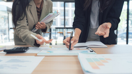 Office Synergy: Colleagues collaborate over documents, charts, and spreadsheets, meticulously...