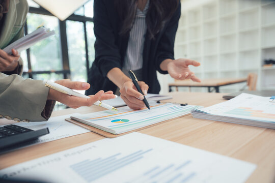Focused Insights: Professionals gather, heads bowed, over reports, exchanging ideas. Their faces etched with concentration, the room hums with strategic energy.