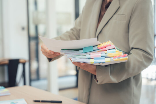 Diligent Review: A person in a formal setting meticulously reviews a stack of organized documents, highlighting a dedicated work ethic and attention to detail.