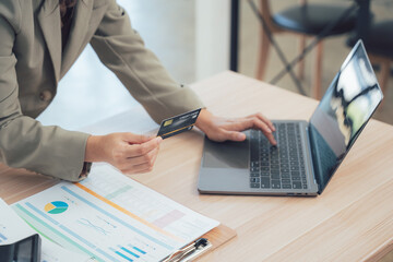 E-commerce Transaction: A person is shown at their desk engaged in a secure online purchase, holding a credit card and typing on a laptop, symbolizing the ease and convenience of digital transactions.