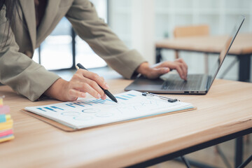 Business Analyst at Work: A diligent business analyst, immersed in data analysis, meticulously reviews a financial report while using a laptop to make quick decisions.