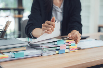 Office Document Management: A focused individual meticulously organizes a stack of files, symbolizing the efficient management of important documents, within the organized office setting.