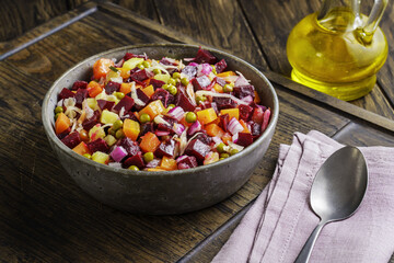 Colorful Russian Vinaigrette salad with beets potatoes and pickles is served in rustic bowl