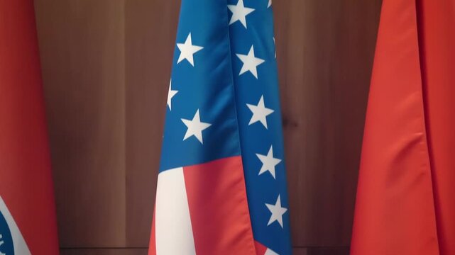 An American flag stands on a floor flagpole among flags of other countries at an international conference. Closeup