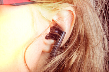 Person listens to music with wireless earbuds in a casual setting during the day