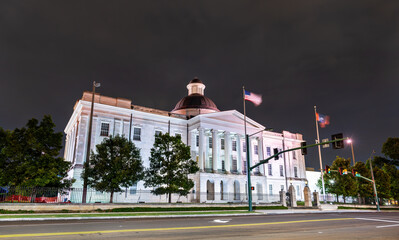 Old Capitol Museum stands in Jackson, Mississippi, USA. Historic Greek Revival architecture features the dome and stone columns illuminated by lights under a dark night sky