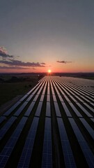 Aerial wide shot of a massive solar panel farm stretching to the horizon at sunset. Rows of photovoltaic panels reflect the golden light of the sun under a picturesque sky, representing renewable ener