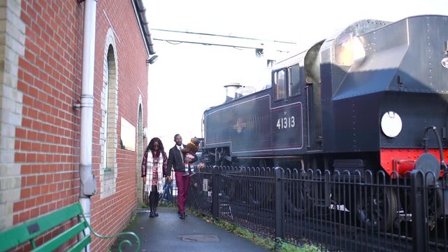 A couple is standing next to a train with the number 4141 on the side. The train is black and has a red front