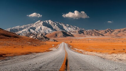 A paved road stretches into a desert landscape, flanked by mountains. Sunlight illuminates the scene