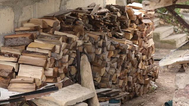 A large stack of chopped firewood logs arranged neatly outdoors. This rustic lumber pile serves as prepared natural fuel for winter heating in a fireplace or stove.

