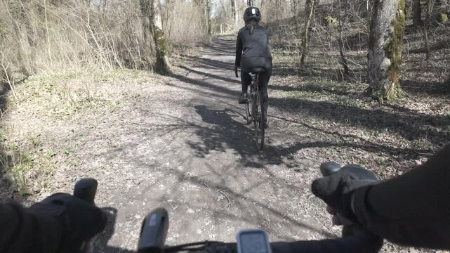 Gravel bike POV riding through forest trail overtaking cyclist and reaching wooden bridge