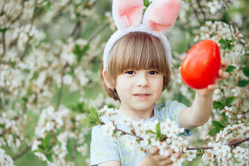 Easter egg hunt. child Wearing Bunny Ears Running To Pick Up Egg In Garden. Easter tradition. Baby with basket full of colorful eggs.