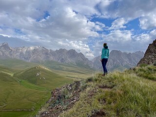 Obraz premium Woman hiking and enjoying the open landscape and natural beauty of mountains in Kel-Suu Valley, Kyrgyzstan.