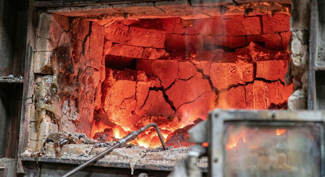 High-temperature furnace interior featuring cracked refractory brickwork and molten slag accumulation