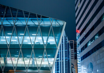 Modern glass office building with illuminated interior in Hong Kong, China. Contemporary corporate architecture symbolizing business transparency, innovation and global economy