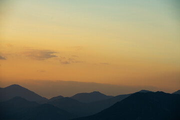 Fototapeta premium Bright sunset over the silhouette mountains at evening time.
