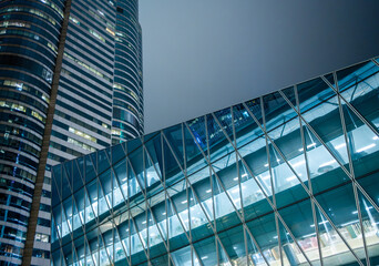 Modern glass office building with illuminated interior in Hong Kong, China. Contemporary corporate architecture symbolizing business transparency, innovation and global economy