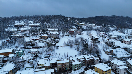 Snow-covered Italian village nestled in a winter landscape with rolling hills Le Bore, Parma, Italy
