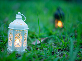 Decorative white lantern (Fanoos) glowing on nature background for Ramadan and Eid Greeting.