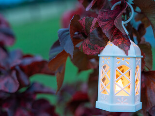 Decorative white lantern (Fanoos) glowing on nature background for Ramadan and Eid Greeting.
