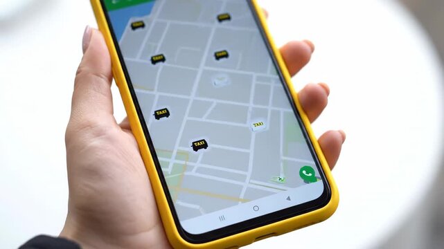 Woman's hand holding a yellow smartphone displaying a ride-sharing app with a map and car icons.