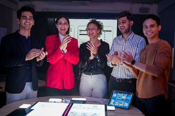 Professional software development team applauding for project success. Happy diverse group clapping hands to celebrate mobile app launch in high-tech startup office.