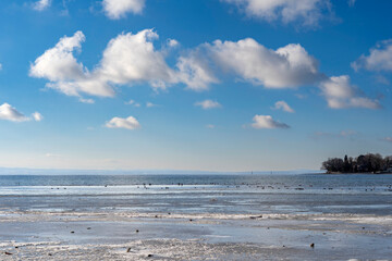 frozen bay of Lake Constance in Wasserburg Germany with blue sky and clouds