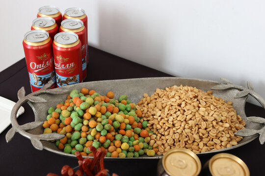 Metal tray with peanuts and snack balls next to Kozel beer cans.