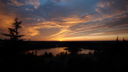 Dramatic sunset sky with warm clouds reflecting over calm water and distant land silhouette