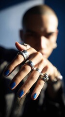 A man in a salon displays his hand with blue nail polish on one finger. He is engaged in a manicure session, showcasing his personal grooming choice