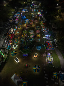 Aerial view of a vibrant carnival illuminated against the dark sky, rides spinning with colorful lights near the waterfront, Nassau, Bahamas.