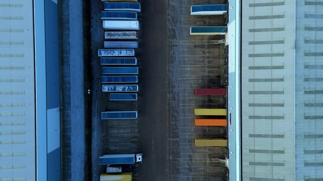 Top down aerial view of semi-trucks and trailers lined up at industrial distribution warehouse, logistics and business transport, cold winter morning Corby, United Kingdom.
