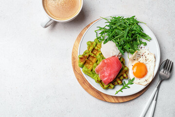 Healthy breakfast with green spinach waffles, salmon, cream cheese, fried egg and salad