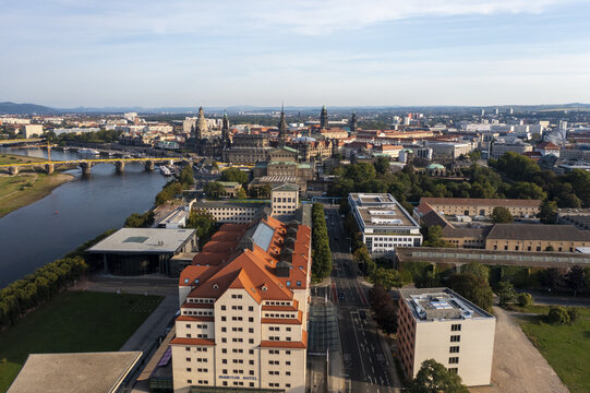 Aerial view of the Elbe River flowing past the majestic Dresden Frauenkirche and Zwinger Palace, a tapestry of terracotta roofs and verdant trees, Dresden, Saxony, Germany.