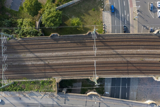 Aerial view of parallel railway tracks cutting through the urban landscape, framed by roads and verdant trees, Dresden, Saxony, Germany.