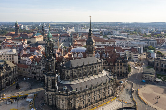 Aerial view of the Hofkirche's dark stone contrasts with the city's red-tiled roofs under a bright sky, with the Dresden Castle spire piercing the skyline, Dresden, Saxony, Germany.