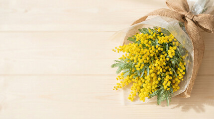 Freshly wrapped bouquet of yellow mimosa flowers on wooden table  