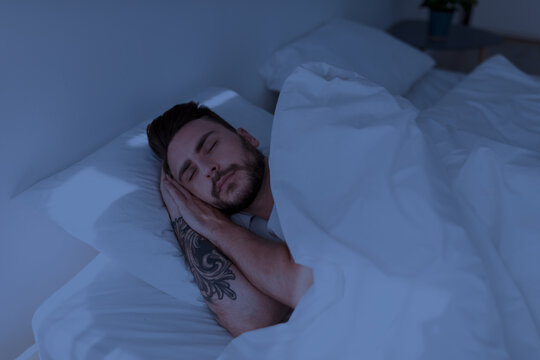 Handsome man see sweet dreams, resting peacefully in his comfortable bed at home. Man lying with eyes closed. Deep male sleep, recreation, time to rest and nap concept