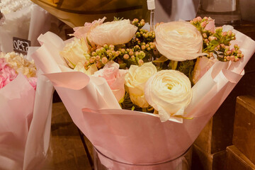 Close-up of beautiful peach roses and white roses arranged in a floral display with soft lighting