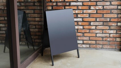 A blank sandwich board sits beside a brick wall, waiting for a message or advertisement to appear.