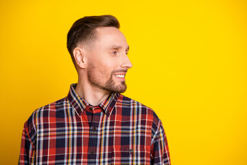 Fototapeta premium Young man in plaid shirt smiles as he looks aside against a bright yellow background for a casual fashion portrait suitable for advertising and lifestyle stock imagery