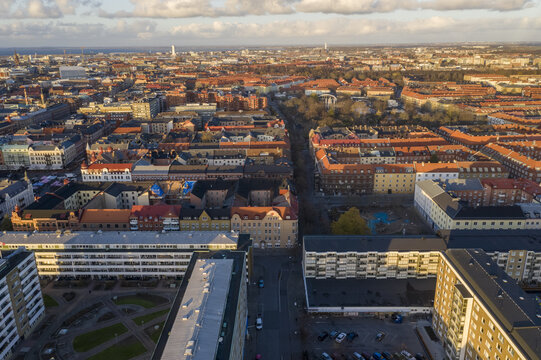 Aerial view of buildings with red and brown rooftops casting shadows under a partly cloudy sky, revealing the urban texture of the city., Malmo, Scania county, Sweden.