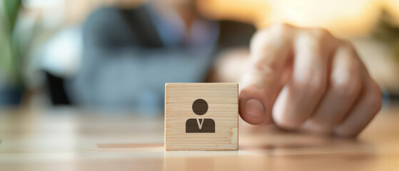 Hand selecting wooden block with person icon among others, representing recruitment, hiring decision, team selection, human resources strategy, leadership choice and workforce management concept.
