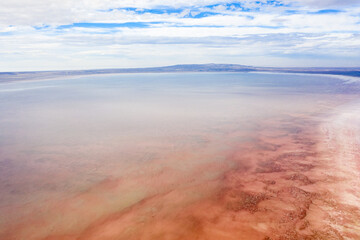 Aerial view of a salt lake painted with shades of pink and orange, contrasted against the blue sky, creating a surreal landscape, Lake Tuz, saray/van, Turkey.