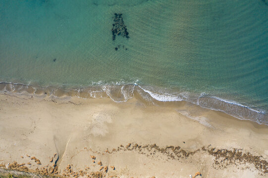 Aerial view of the tranquil silver beach where the turquoise waters meet the sandy shore, bordered by a line of trees, Kusadasi, Aydin, Turkey.
