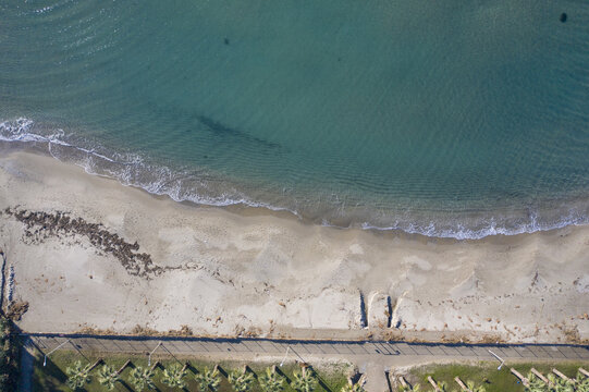 Aerial view of the tranquil silver beach where the turquoise waters meet the sandy shore, bordered by a line of trees, Kusadasi, Aydin, Turkey.