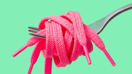 Pink shoelace wrapped around a silver fork imitating spaghetti isolated on a pastel green background