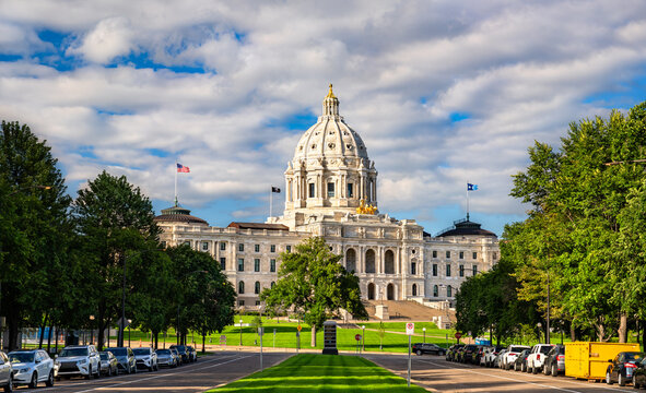Minnesota State Capitol in Saint Paul, USA. Historic Beaux-Arts architecture features the white marble dome and golden Quadriga statue under a blue sky with clouds
