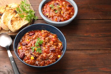 Fototapeta premium Delicious chili con carne served on wooden table, closeup. Space for text